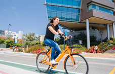 Student riding on an electric bike through campus