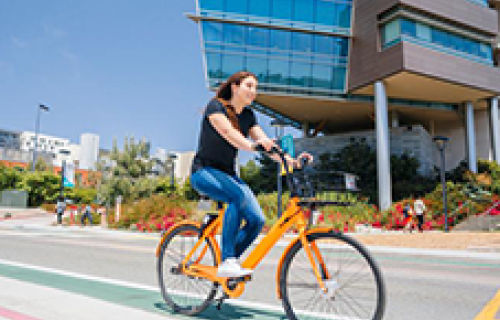 Student riding on an electric bike through campus