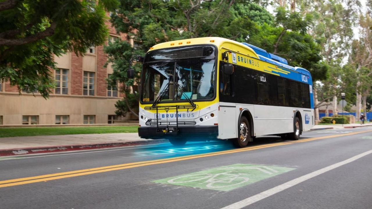 BruinBus with driving down street with artist rendering of electric charging roadway