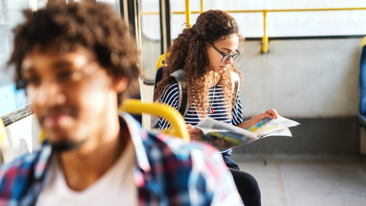 Young women reading newspaper and sitting while waiting bus to start