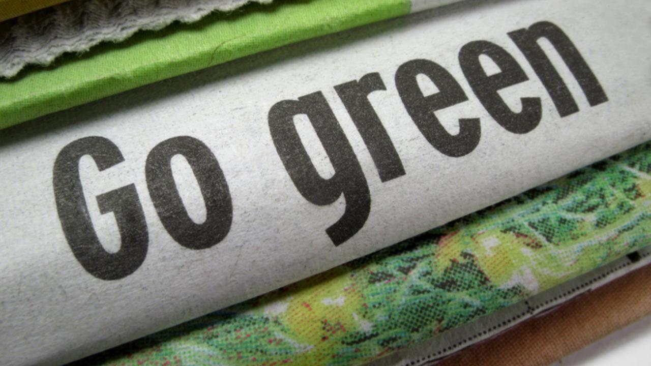 Stack of newspapers with middle one reading Go Green