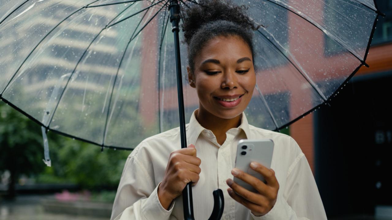 Lady with an umbrella looking at her phone.