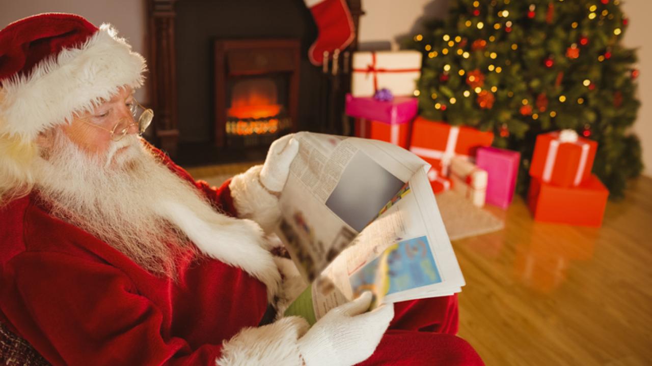Santa reading the newspaper inside a home.