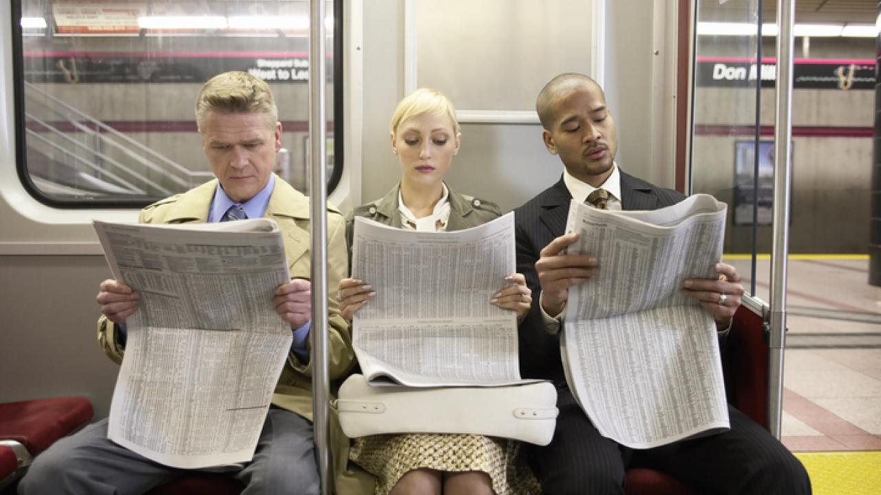 Transit riders reading the newspaper.