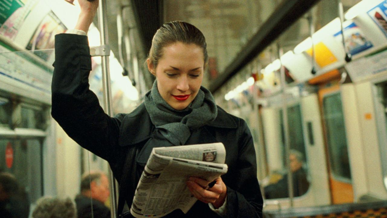 Woman transit passenger reading the paper.
