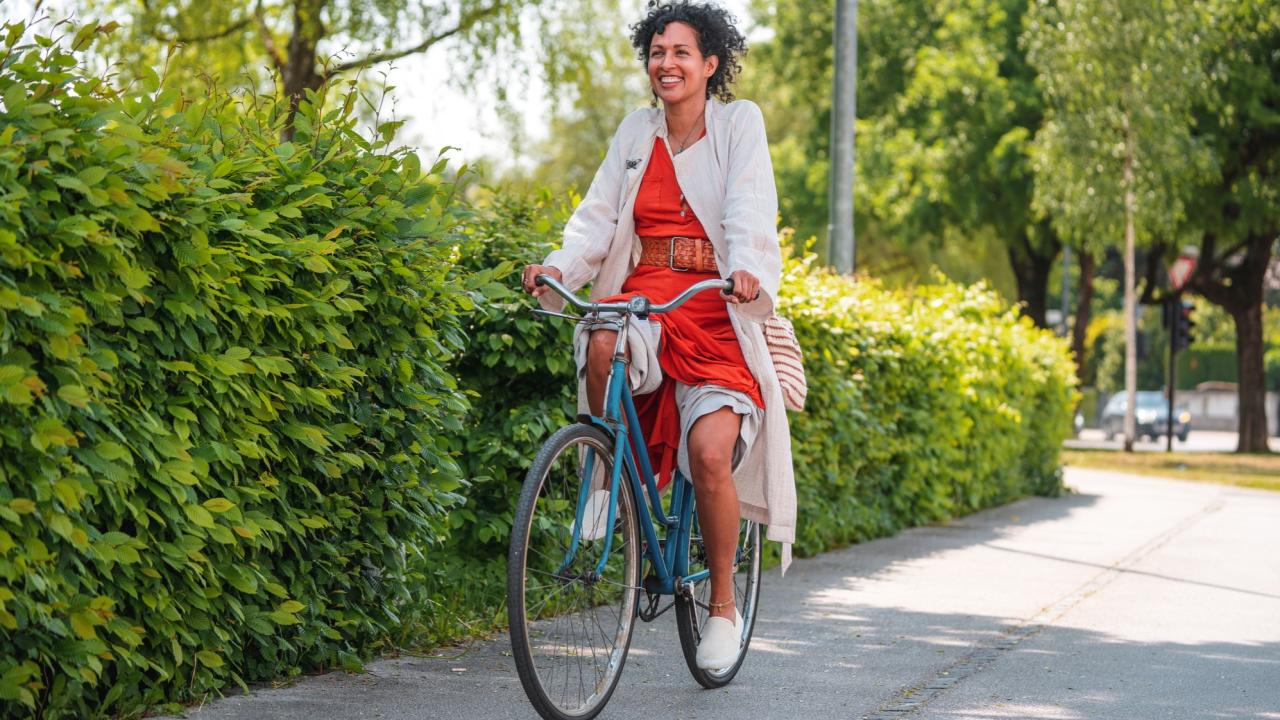 Woman riding a bike with green bushes in the background