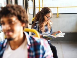 A young women reading a paper on the bus.