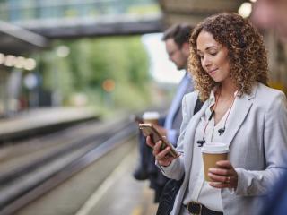 Woman waiting at a rail station reading a newspaper.