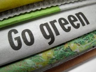 Stack of newspapers with middle one reading Go Green