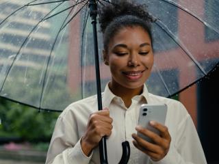 Lady with an umbrella looking at her phone.