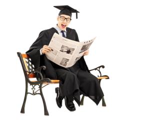 College graduate seated in a chair reading a newspaper