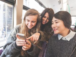 Three women looking at a smart phone on the bus