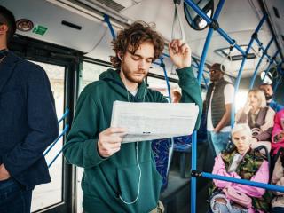 Bearded man reading a newspaper on the bus