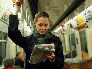 Female transit rider reading the paper.