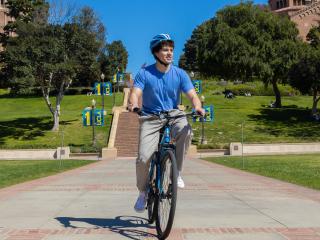 Male student riding a bike with Janss Steps in the background
