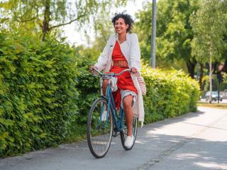 Woman riding a bike with green bushes in the background
